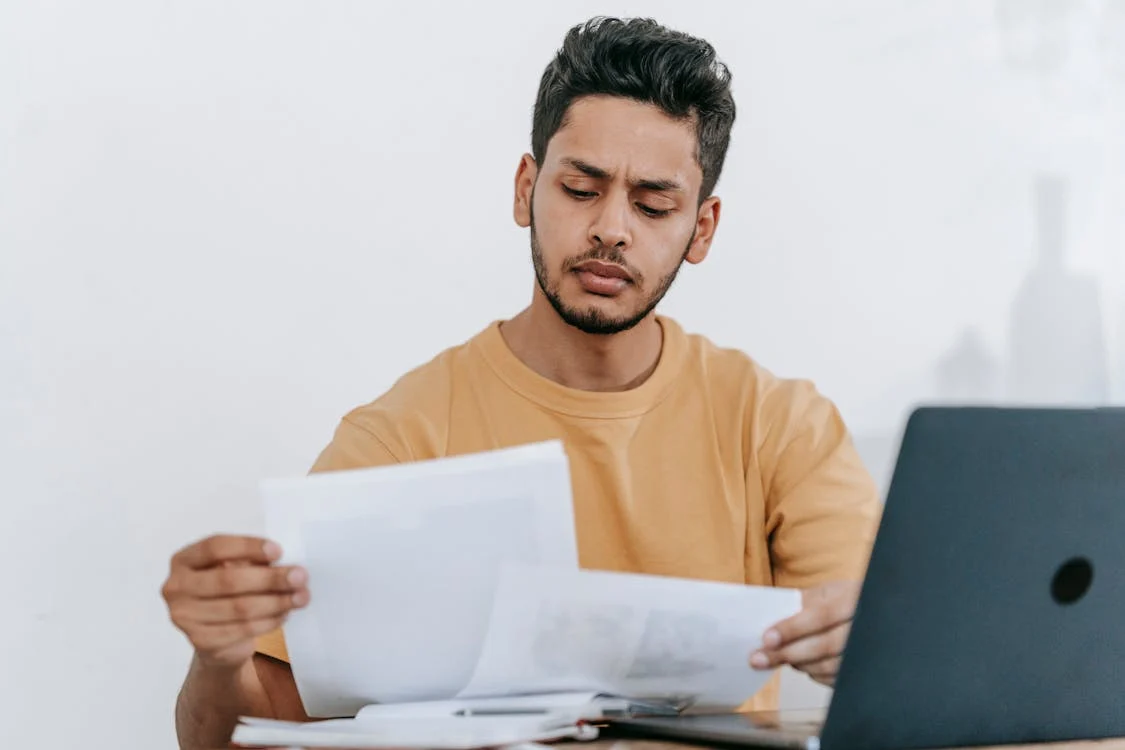 law student seated in front of laptop, looking at papers