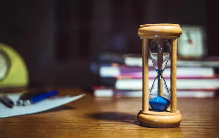 hourglass on wooden table with study materials in background