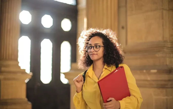 woman wearing yellow holding red folder