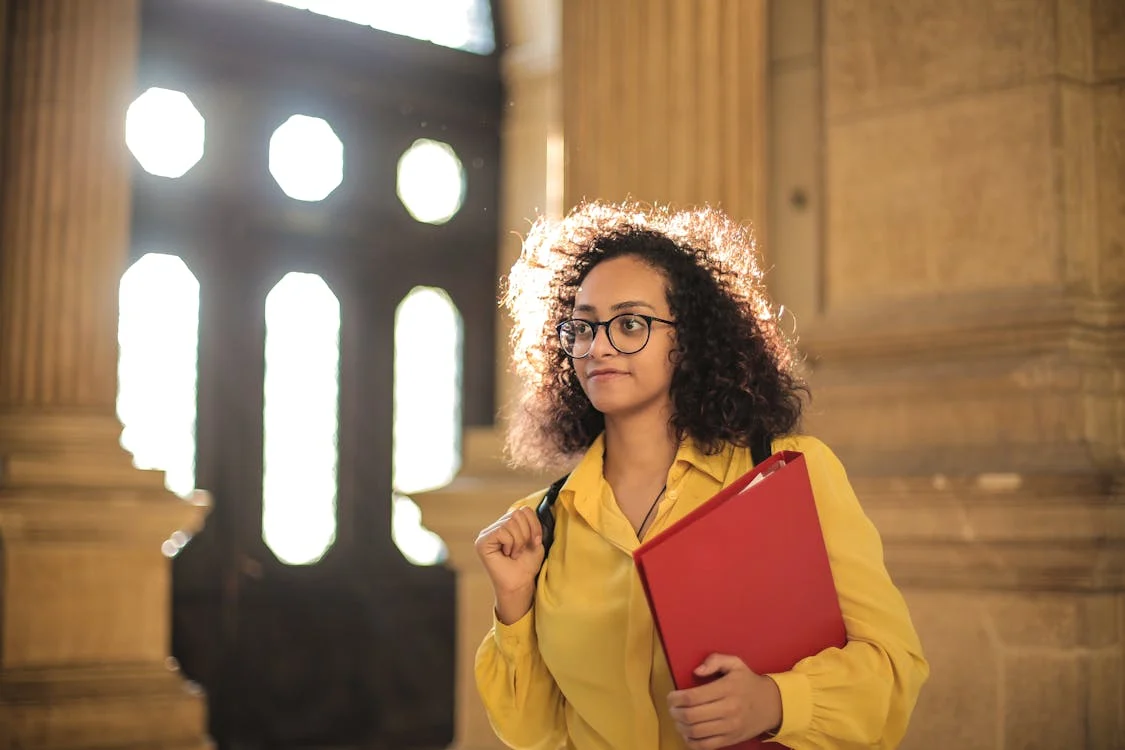 woman wearing yellow holding red folder