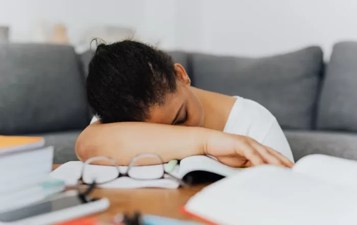 woman resting head on study materials