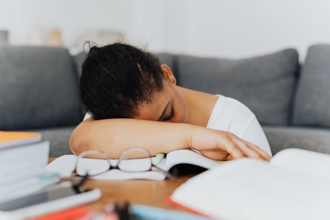 woman resting head on study materials