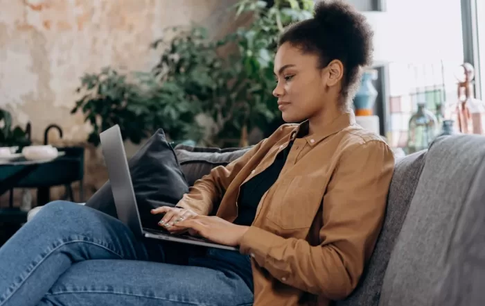 woman sitting on couch using laptop