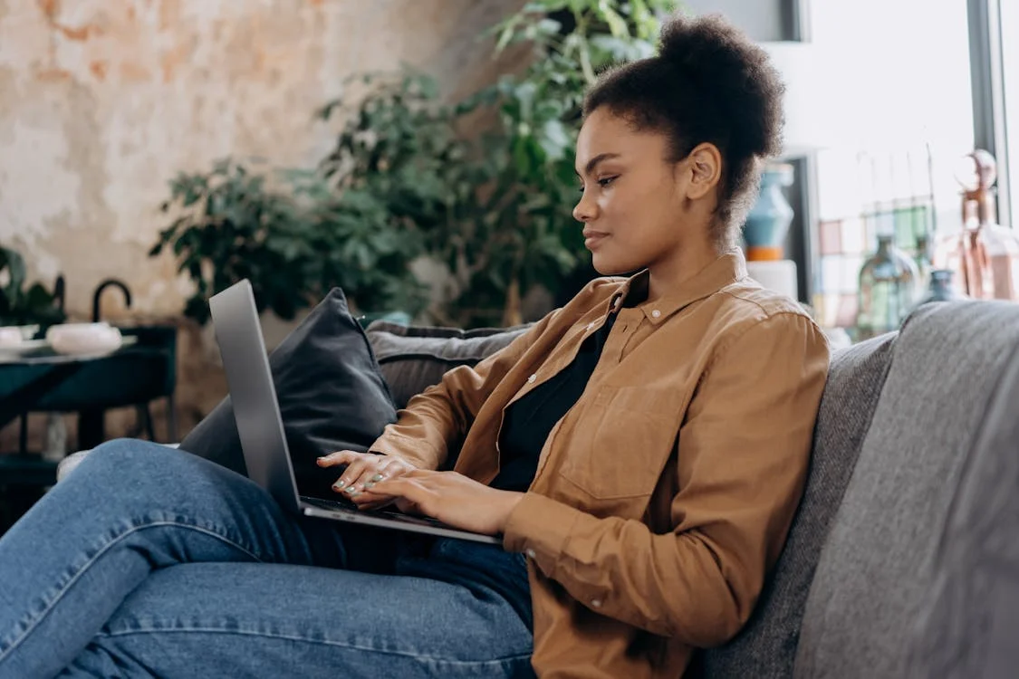 woman sitting on couch using laptop