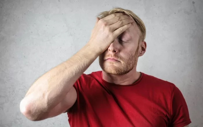 man in red shirt holding head in frustration