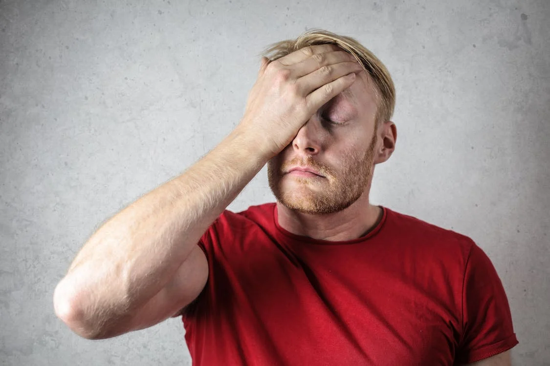 man in red shirt holding head in frustration